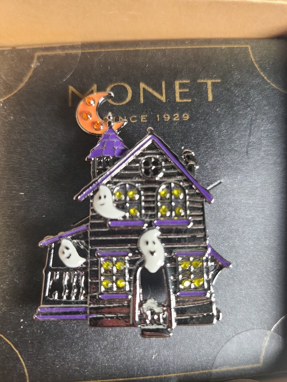 Monet brand enamel pin featuring a haunted house design with ghosts and a cresce